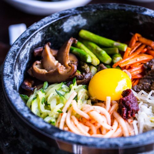 Bibimbap in Dolsot (Stone Pot) with vegetables and beef and egg yolk on top