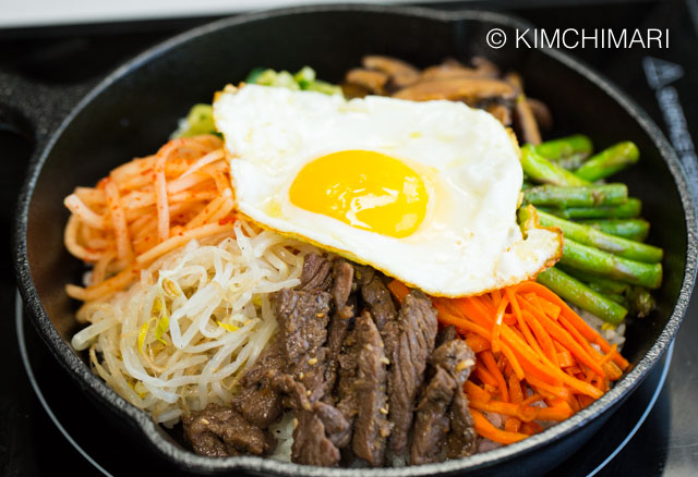 Bibimbap in 8 inch cast iron pan with fried egg on top of vegetables and beef